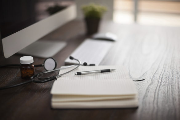 Closeup of a doctor's desk with a stethoscope and a notepad with shallow depth of field