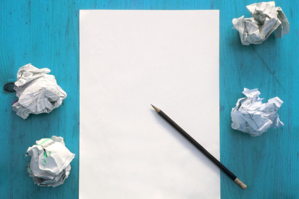 Photo of a sheet of paper, pencil and crumpled paper on a desk.