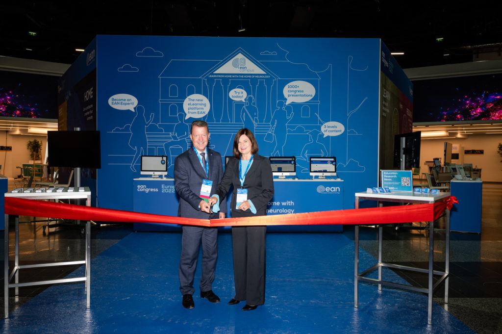 Two people standing side-by-side, cutting a red ribbon at an opening ceremony