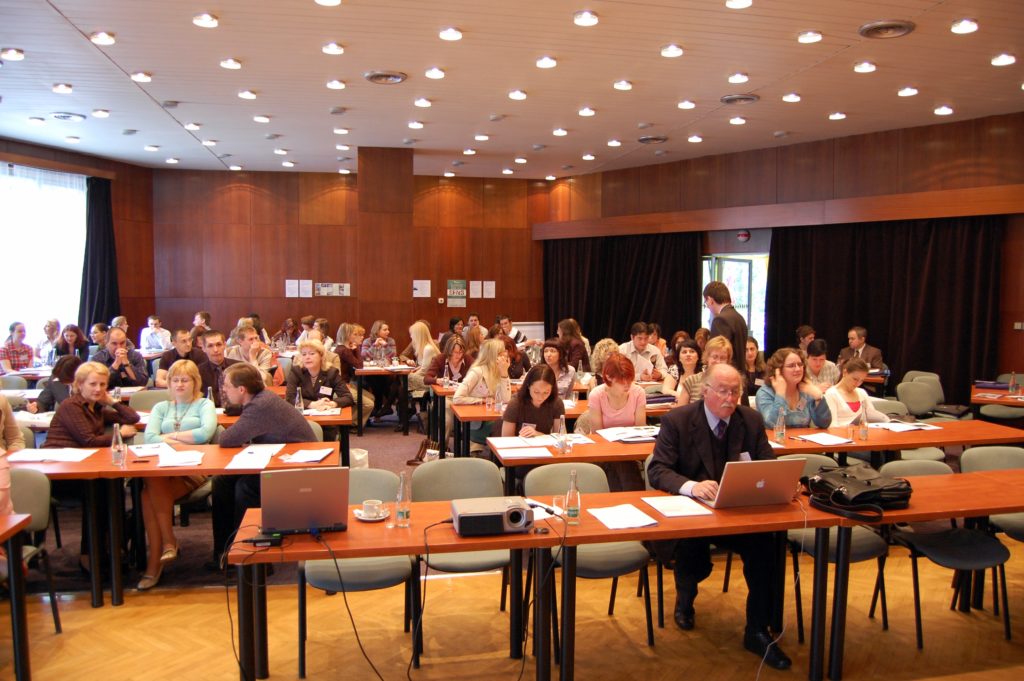 Lecture room full of people seated at tables