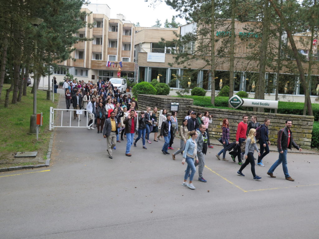 Large group of people walking down a driveway and through a gate outside a hotel