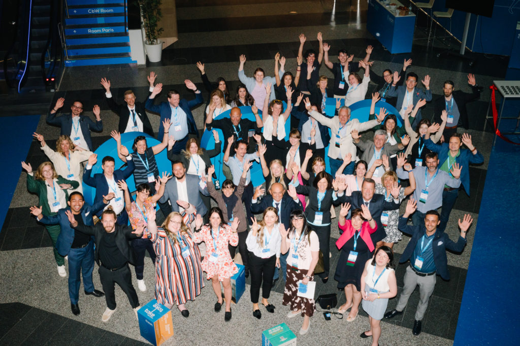 Photo of a large group of people waving at camera, taken from above