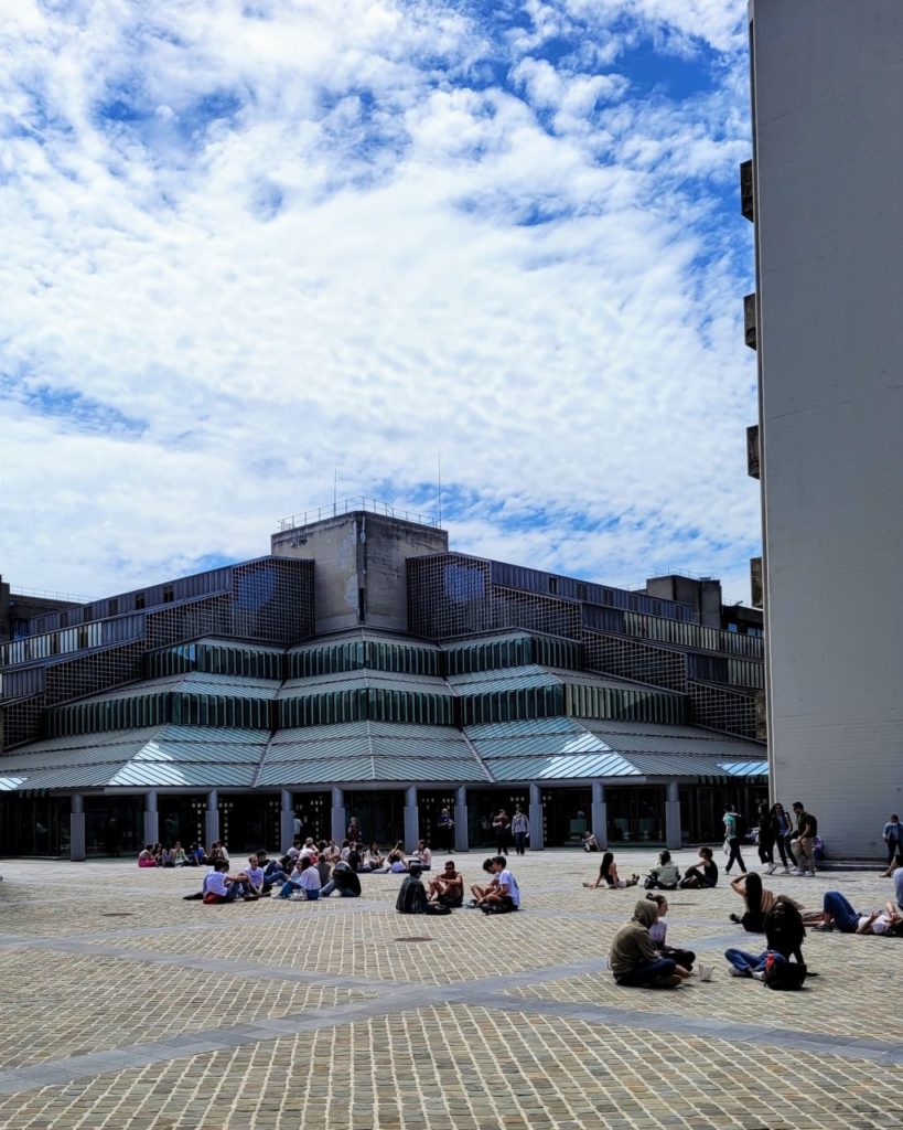 Modern university building with partly cloudy sky