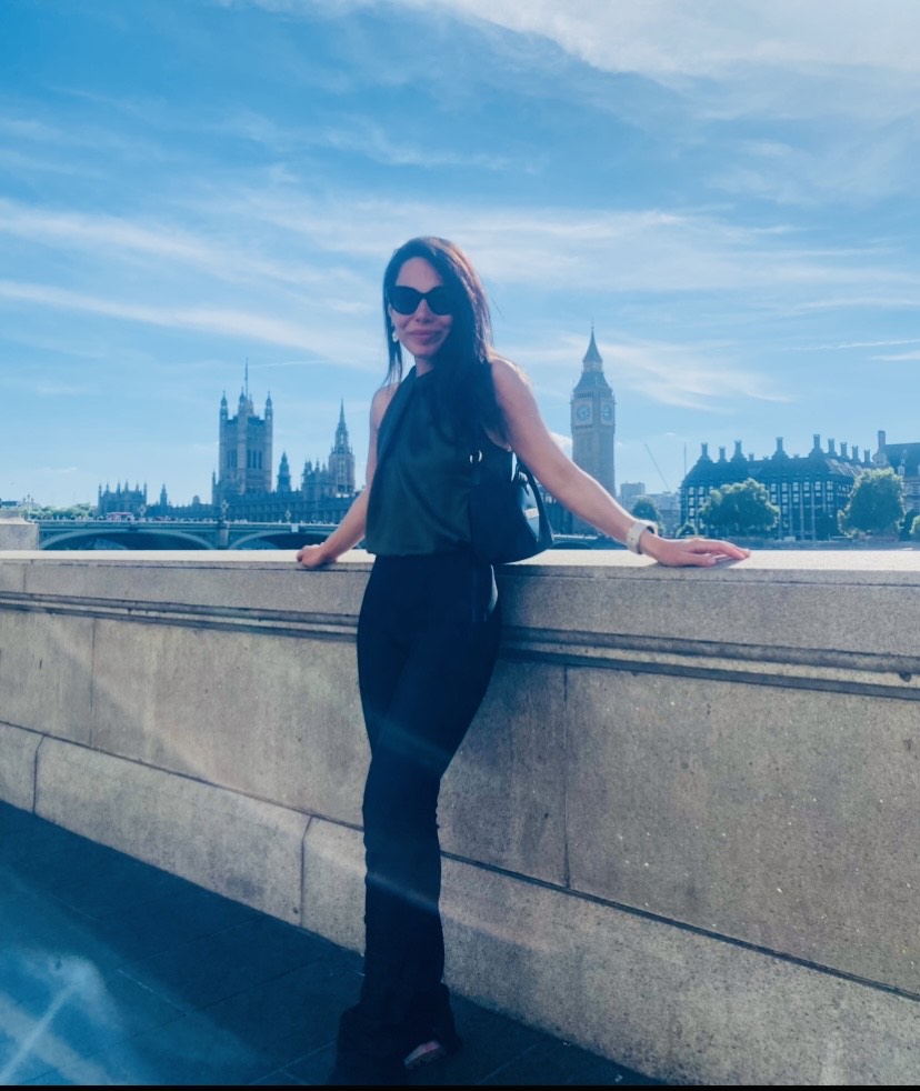 Woman leaning on wall with Palace of Westminster in background