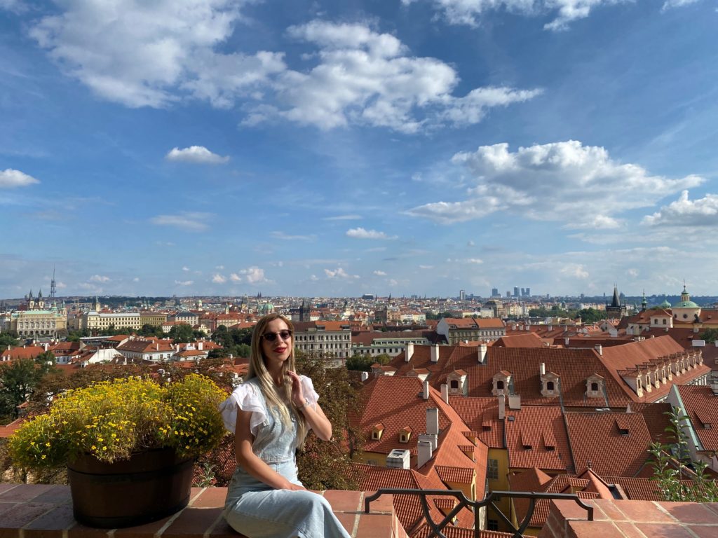 Woman seated on low wall with panorama of rooftops in background