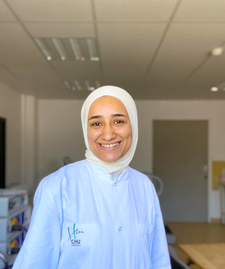 Photo of a woman in white hospital staff clothing, smiling at the camera