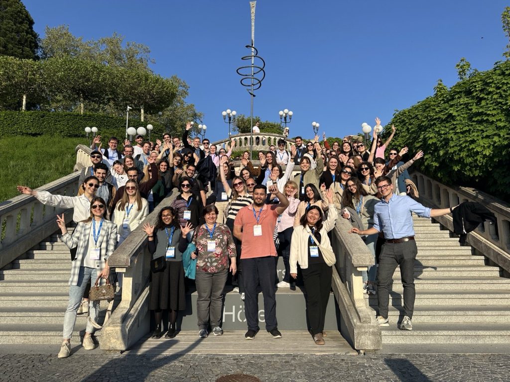 Large group of people posing and waving on an outdoor stairway