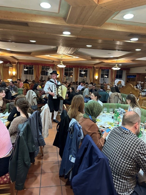 People seated indoors at a restaurant with an accordian player standing between tables