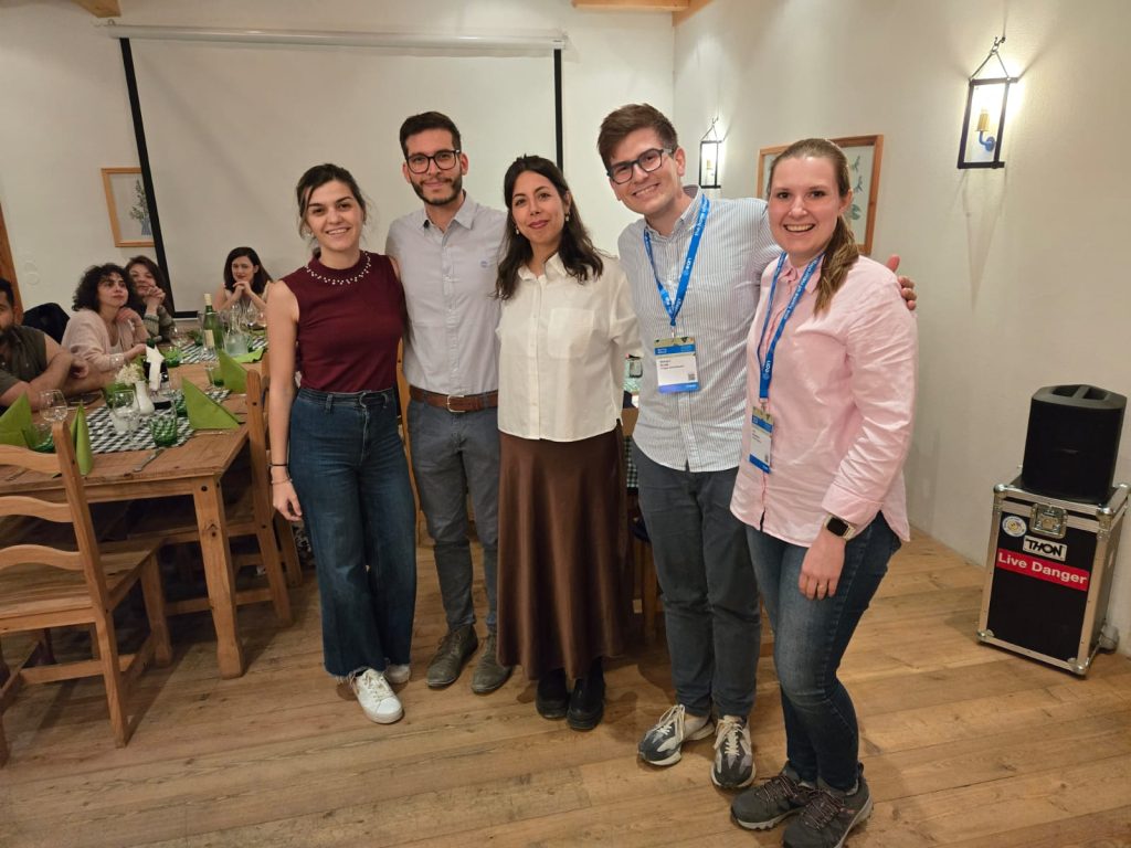 Five people standing, posing for a photo in a restaurant